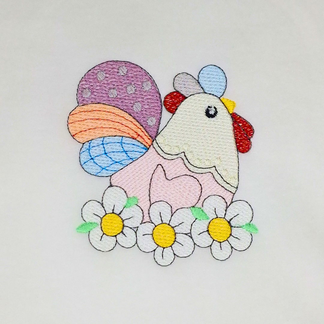 This is an image of a country inspired machine embroidery design by Stitches & Strokes, featuring a colorful hen laying on a nest made of flowers. This Chicken machine embroidery pattern is perfect for embroidery on kitchen items like aprons, dish towels, table runners, and oven mittens.