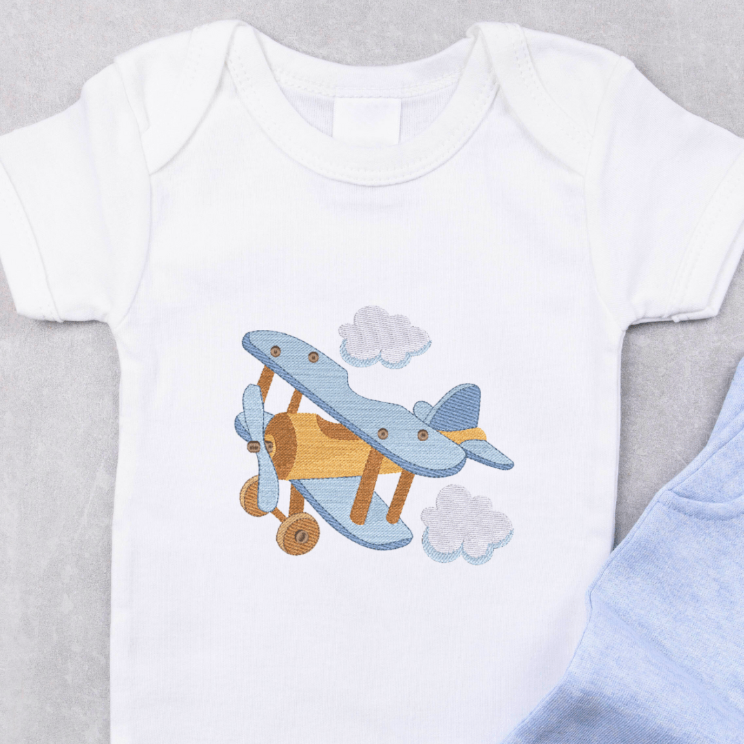 This is a beautiful blue and brown airpane in flight surrounded by clouds machine embroidery design for baby boys. This is an example of what the design would look like embroidered on a baby onesie.