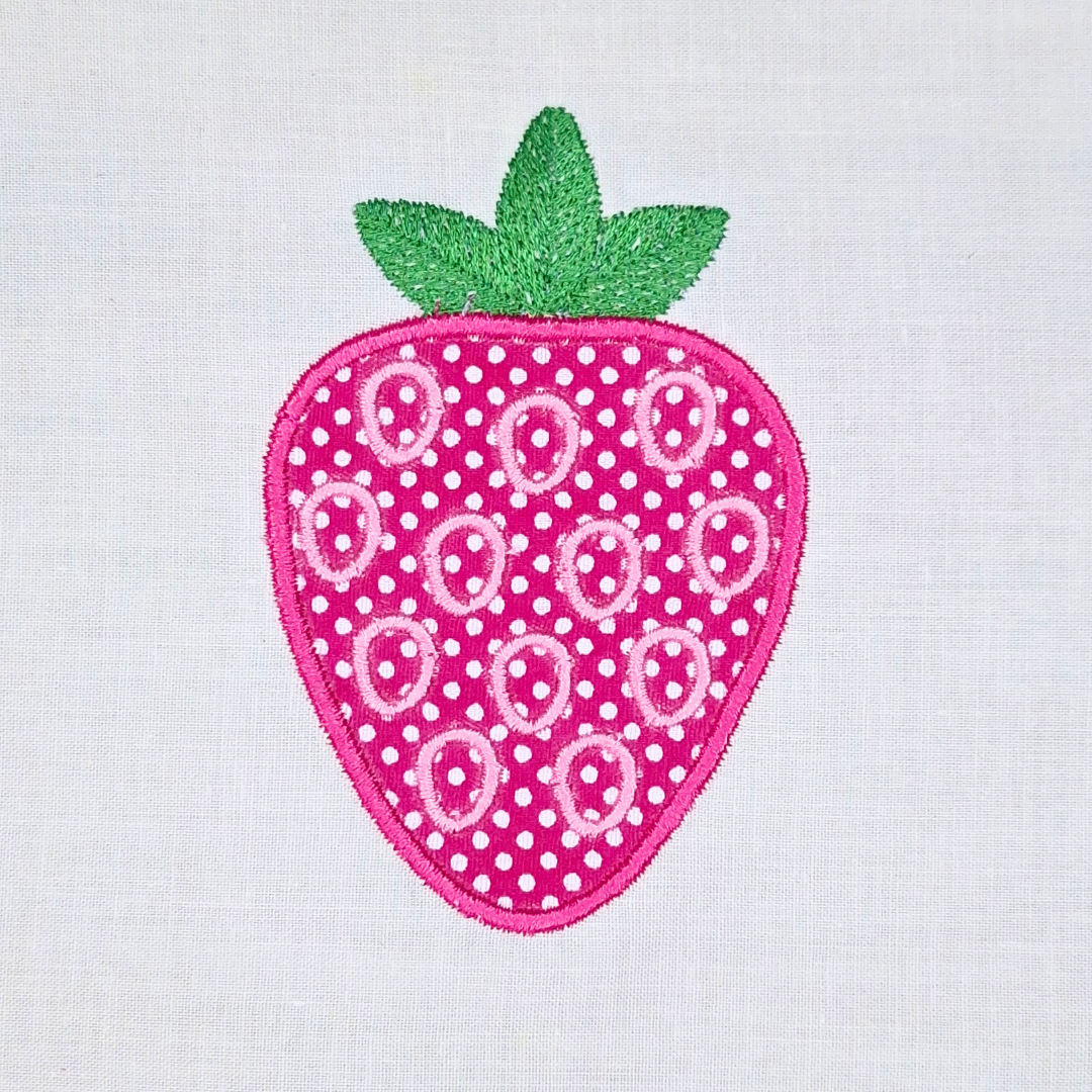 This is an image of an applique machine embroidery design by Stitches & Strokes, featuring a cute strawberry with green embroidered leaves. This strawberry machine embroidery design is perfect for embroidery on kitchen décor and kids clothing.