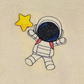 This is an image of an astronaut machine embroidery design. The figure is depicted in a classic spacesuit, featuring intricate details and accented with a star. The embroidery adds a touch of whimsy and celestial charm, making the astronaut appear as if it is floating through a starry cosmos. The design captures a sense of adventure and wonder, perfect for space enthusiasts and dreamers alike.