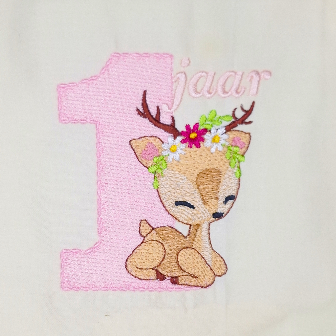 This is an image of a machine embroidery design featuring a baby deer with flowers on it's head and a pink number one in the background. This baby deer with number one machine embroidery design is perfect to compliment your baby girl's first birthday party. Embroider on onesies, t-shirts, and dresses.