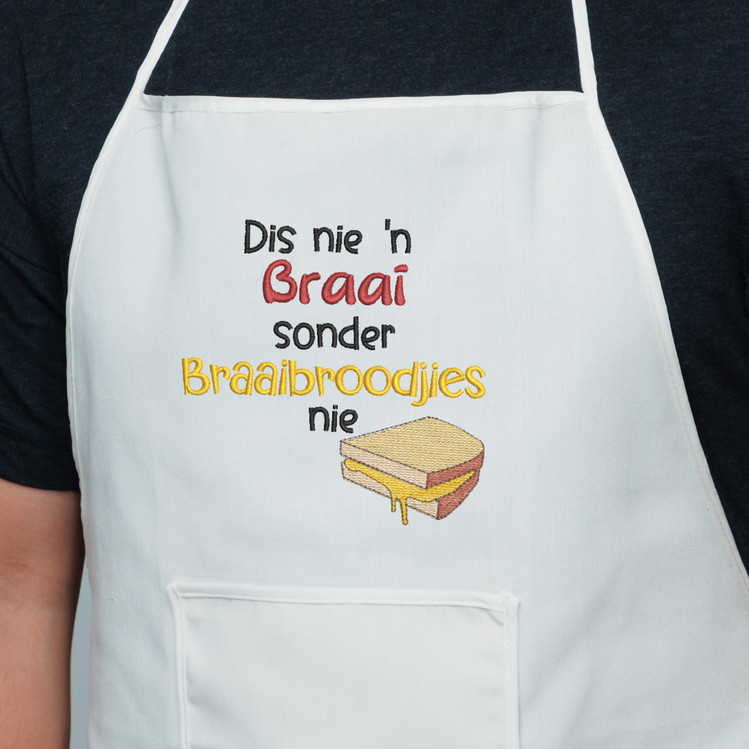 This is an image of a machine embroidery design featuring an Afrikaans braaibroodjie quote: "Dis nie "n braai sonder braaibroodjies nie" that can be embroidered for men on aprons and t-shirts. This braai -themed machine embroidery design is perfect for Father's Day, and Birthday Gifts.