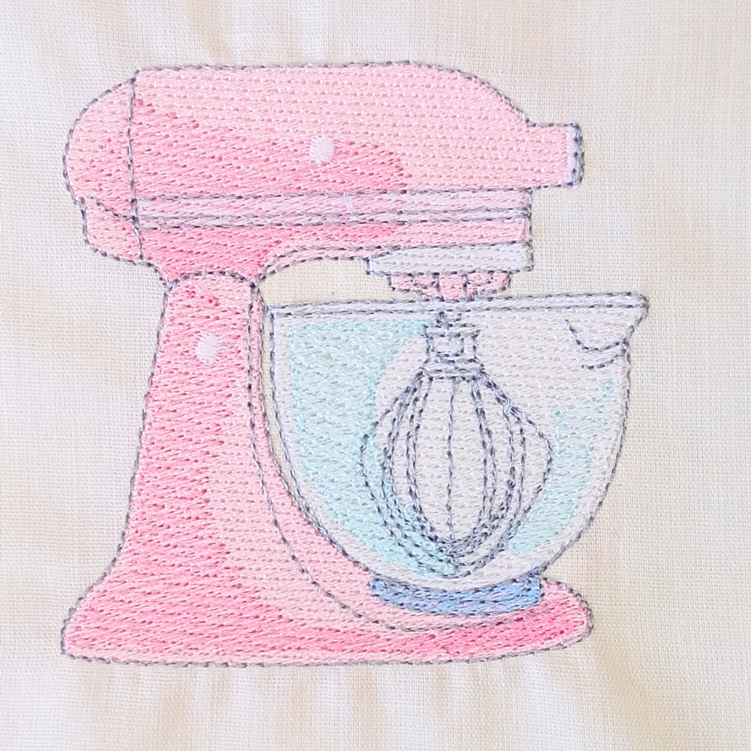 This is an image of a machine embroidery design by Stitches & Strokes, featuring a pink Kitchen Aid electric beater (mixer) for embroidery on aprons, tea towels, oven mittens, and more. This Kitchen Aid electric beater is the perfect machine embroidery design to embroider for mom or grandma on mother's day.