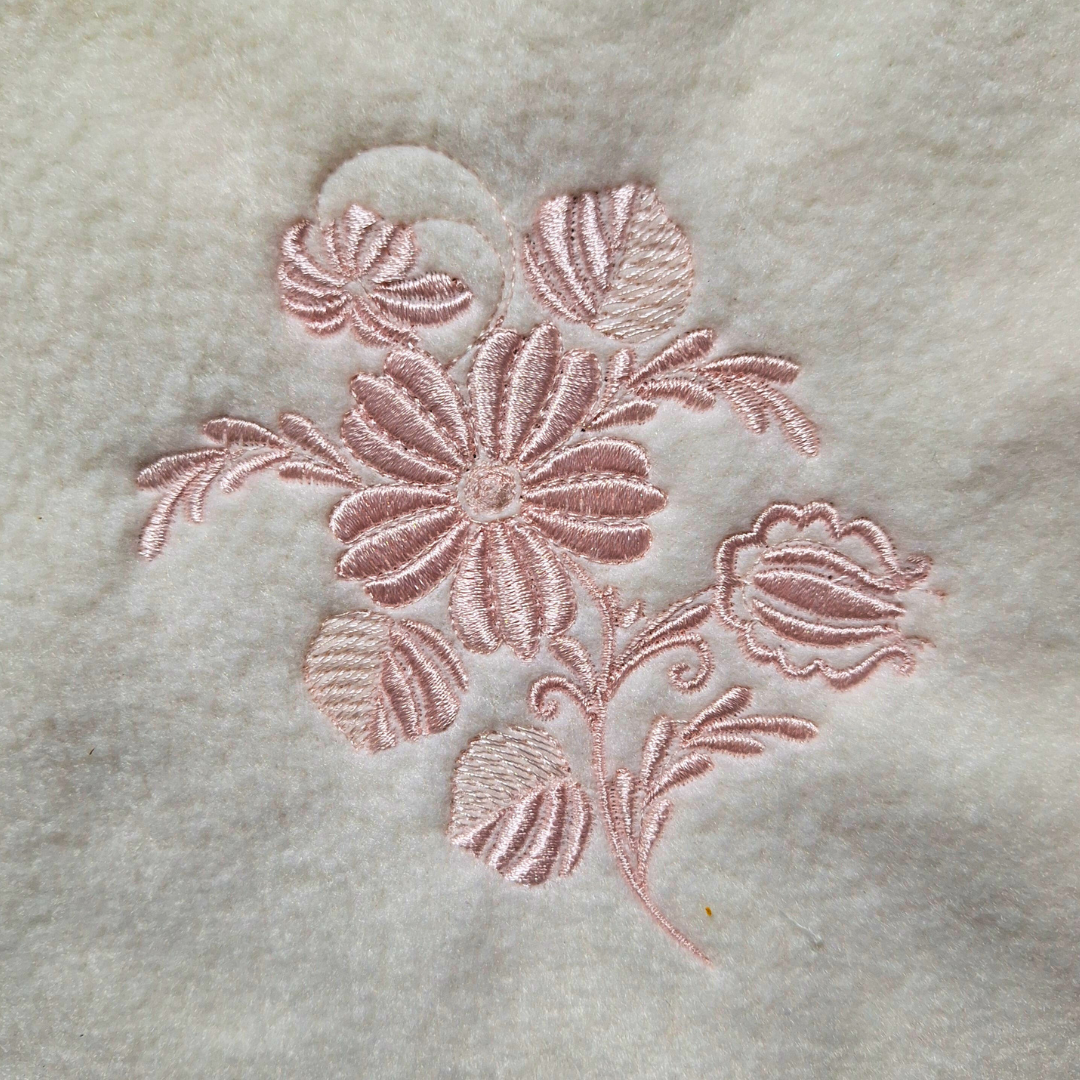 This is an image of a machine embroidery design featuring a detailed flower spray. This flower spray machine embroidery pattern is designed for embroidery on linen, tea towels, and bath towels. The flower spray design is perfect for guest rooms and as gifts for bridal showers, weddings, birthdays, and mother's day.