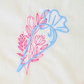 This is an image of a machine embroidery design by Stitches and Strokes, featuring a cake and cookie decorating themed piping bag in Satin stitches, with a flower motif in Running stitches. This Piping Bag Machine embroidery pattern is perfect for embroidery on aprons and kitchen décor for cake decorators.