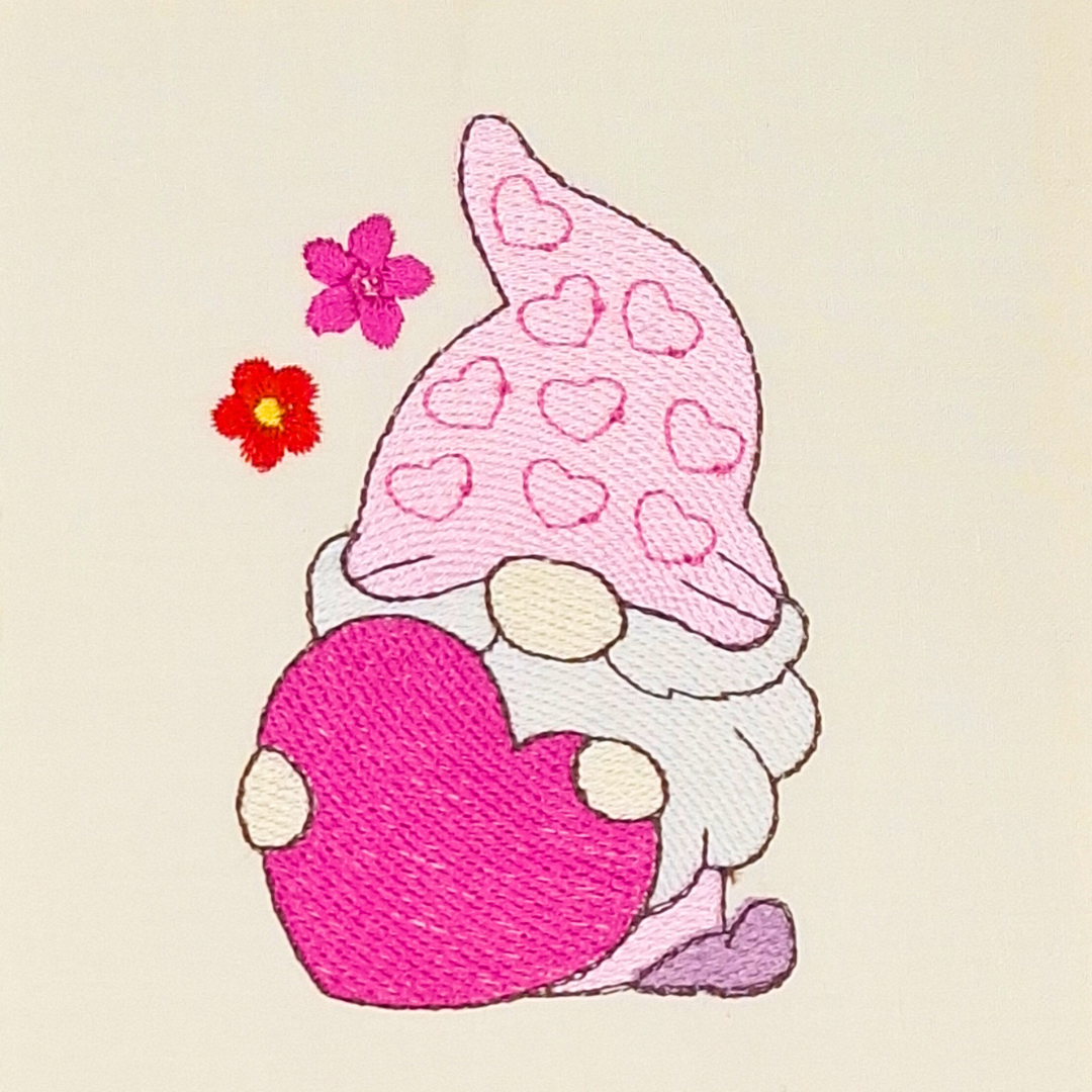 This is an image of a Valentine's Gnome machine embroidery design, featuring a pink hat and holding a bright pink heart. This Gnome machine embroidery design is perfect to show your love on Valentine's Day by embroidering it on gifts like bags, pencil cases, t-shirts, and more.