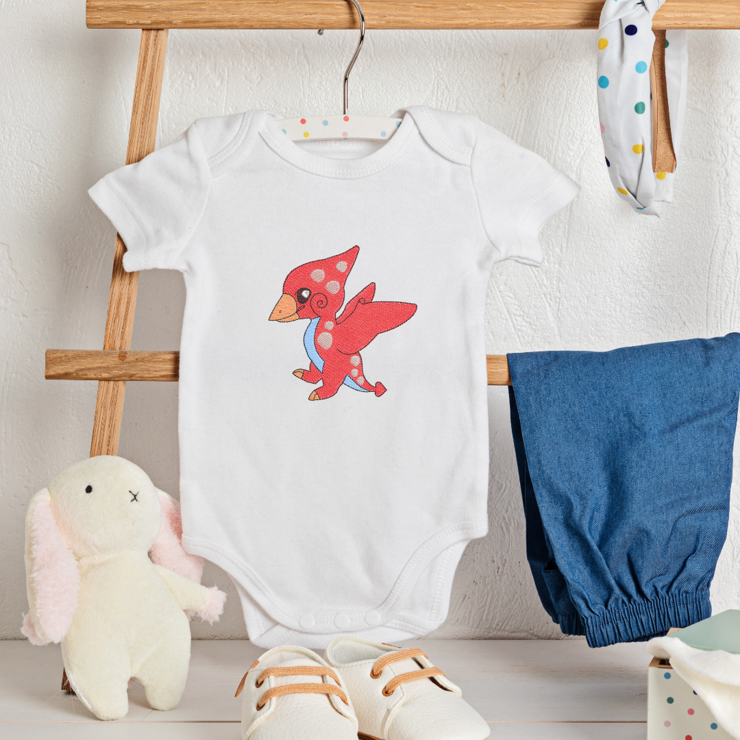 This is an image of a baby Pterodactyl dinosaur machine embroidery design for baby and toddler clothes and t-shirts. This images shows the Pterodactyl dinosaur machine embroidery design embroidered on a baby onesie.