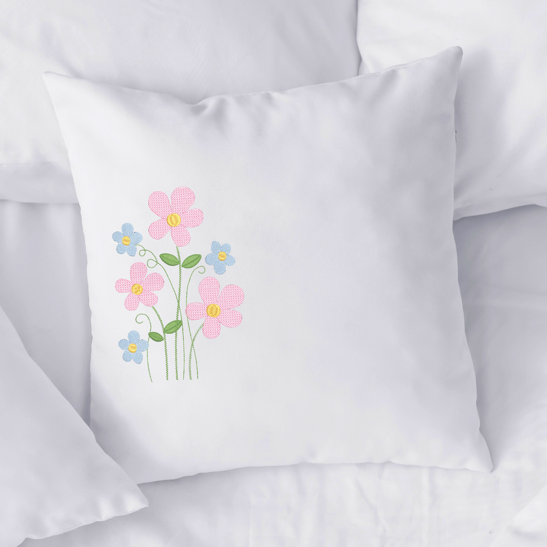 This is an image of a machine embroidery design by Stitches & Strokes, featuring pink, and blue field flowers. This Spring wild flower machine embroidery design is perfect for embroidery on pillowcases, shirts, girl's dresses, and more.